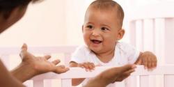 Baby in crib, smiling at mom