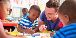 a teacher observing a child drawing with crayons