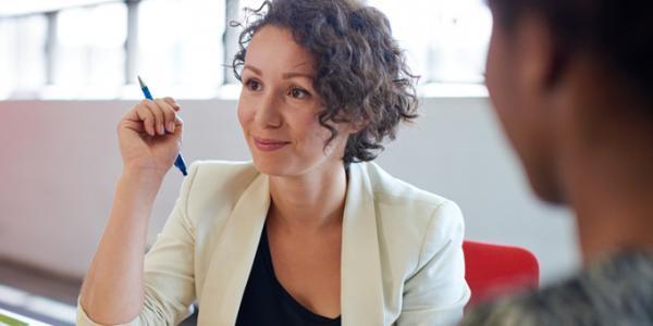 Woman holding pen and listening to someone speak