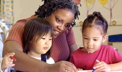 Teacher helping two students with writing