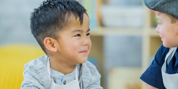 Two preschoolers smiling at each another