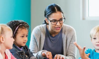 A teacher talking with a group of young children.