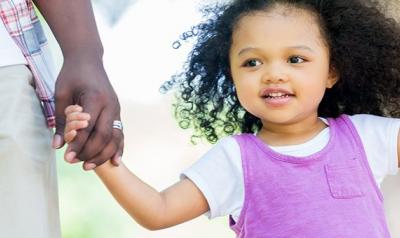 Young girl holding her parent's hands outside