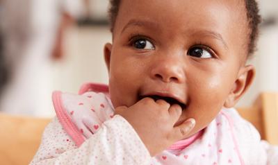 Little baby smiling with her fingers in her mouth