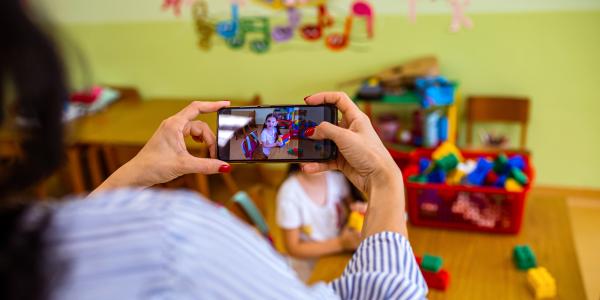 Teacher photographing a child as they build with blocks