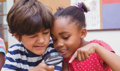 Two children looking through magnifying glass