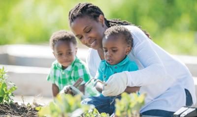 Teacher helping two preschoolers with gardening