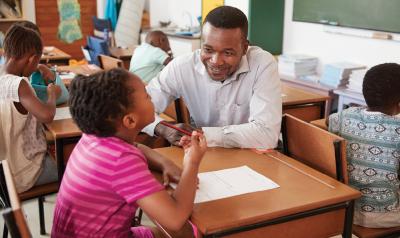 Male teacher helping student in classroom