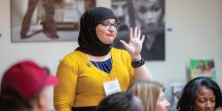 a person raising their hand to speak in a room full of people