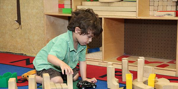 Young child playing on the floor in the block center of a classroom