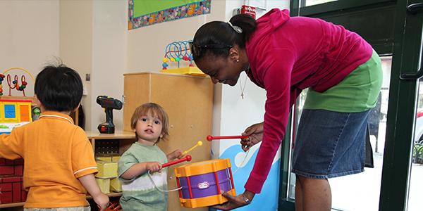 Teacher plays with a young child using a drum