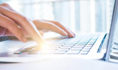 A picture of someone typing on a laptop