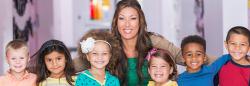 Teacher and preschoolers smiling in a classroom