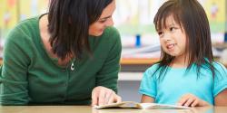 a teacher reading with a child at a table