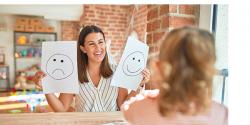 A parent shows a child a picture of a happy and a sad face.