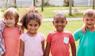 Group of children smiling at the camera while standing outdoors.