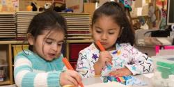 Two young children draw with markers