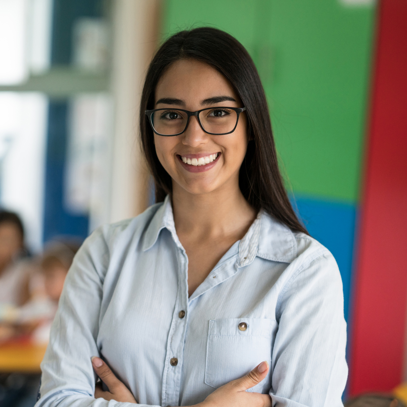 Smiling teacher in front of a classroom.