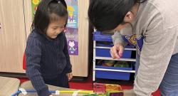 a young girl and a teacher playing with a craft