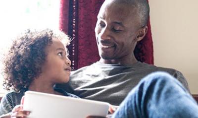 father and son with ipad smiling