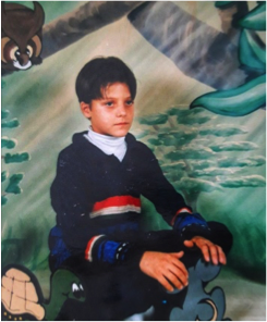 A picture of the author in 3rd grade.  Shows a boy sitting in front of a painted background.