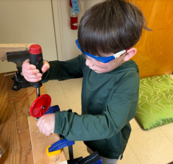 a young child with safety goggles using some tools