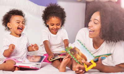 Mother reading and laughing with her two young daughters