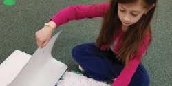 a child looking through a stack of large drawings