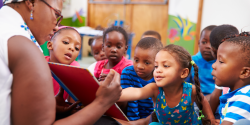 children looking at a book with a teacher