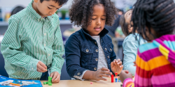 children at a table tinkering with toys